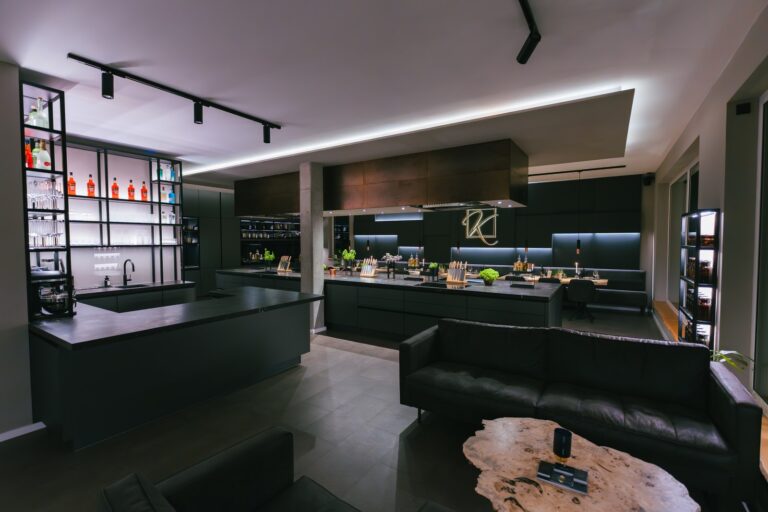 hochzeit & kleine hochzeitsfeier paderborn — kochkurs eventlocation 12 Dunkle Lounge mit Ledersofas, beleuchteter Bar und Kochinseln – Eventlocation für Hochzeitsfeiern in Paderborn