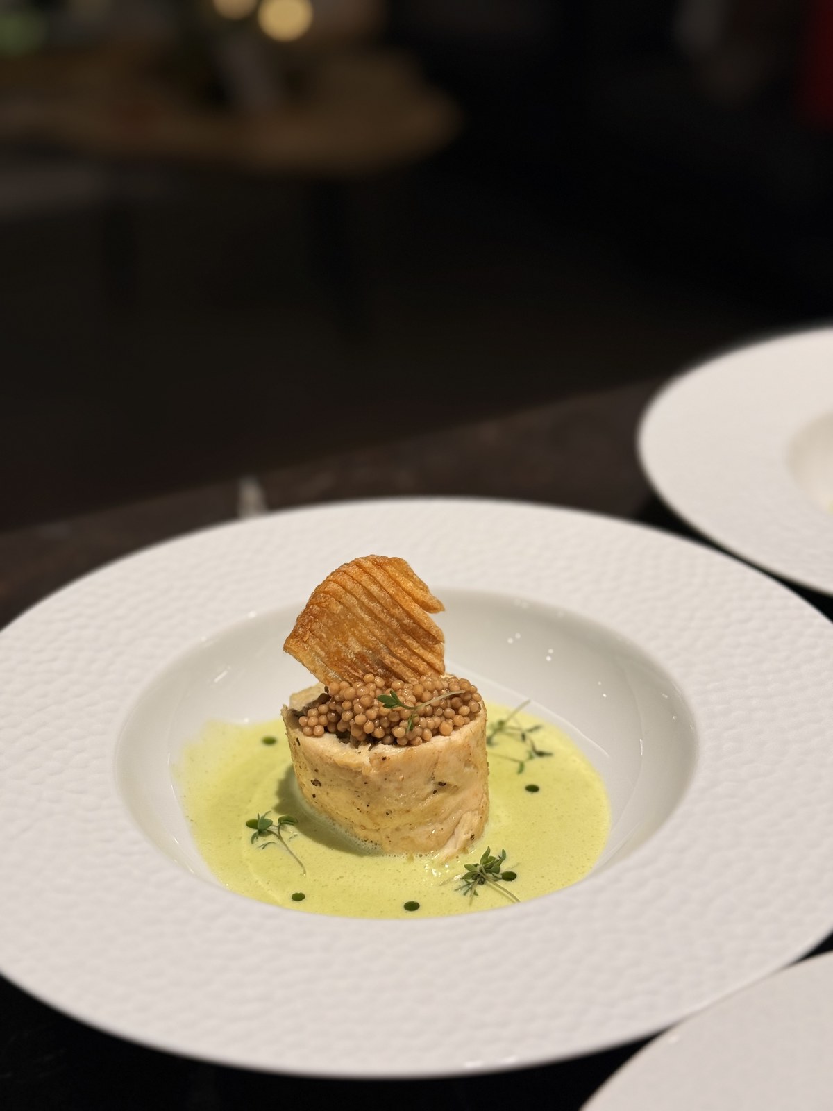 Eleganter Hauptgang mit Fisch und gruener Schaumsauce auf weissem Teller